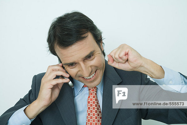 Businessman using cell phone  smiling  and making fist