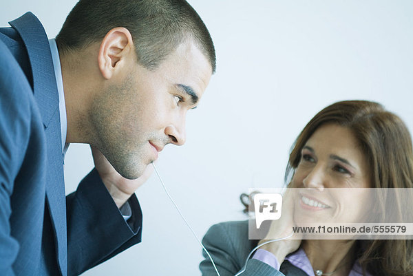 Business colleagues sharing earphones