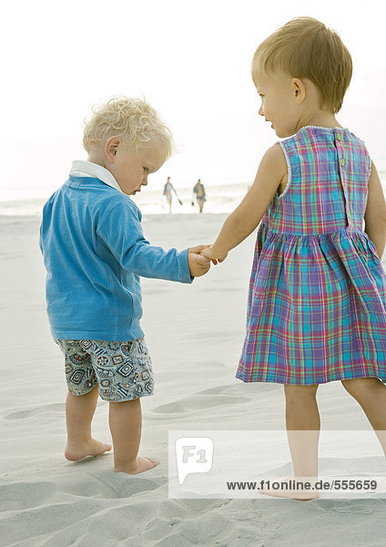 Zwei Kleinkinder am Strand stehend  Rückansicht