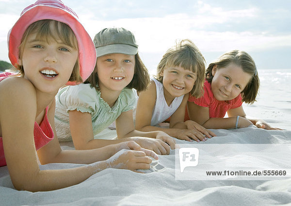 Vier Mädchen am Strand liegend  lächelnd vor der Kamera  Nahaufnahme