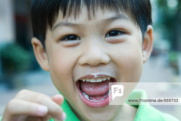 Boy with mouth wide open and food stains around mouth  looking at camera
