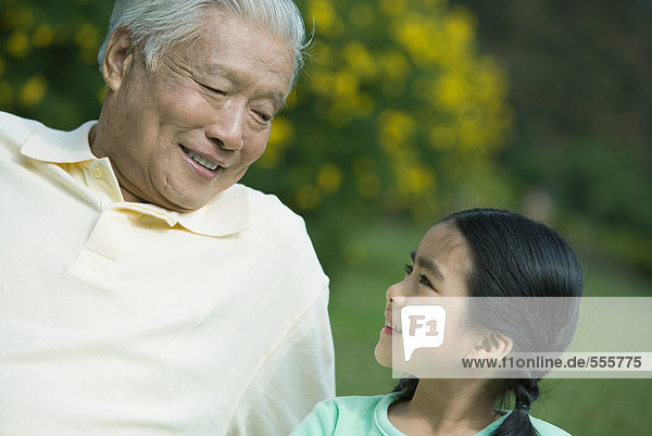 Mädchen und Großvater lächeln sich an.