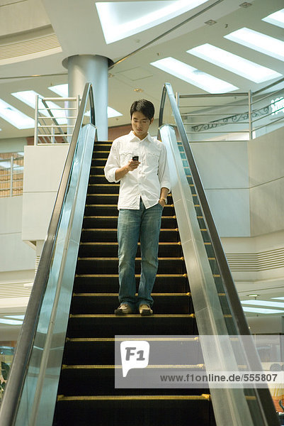 Mann auf der Rolltreppe überprüft Handy