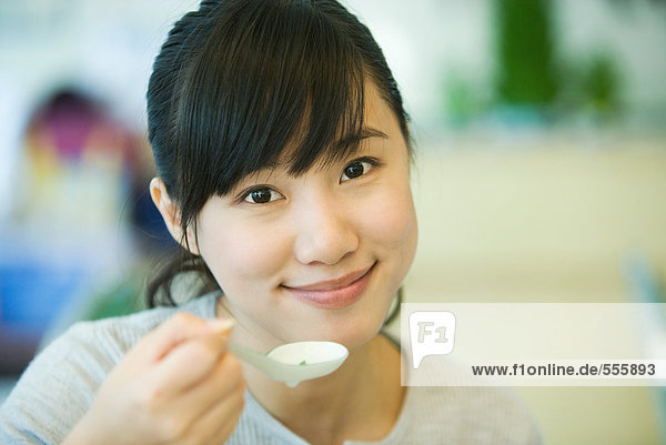 Woman holding up spoon  smiling at camera