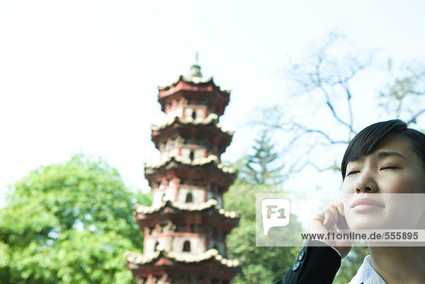 Woman using cell phone  pagoda in background