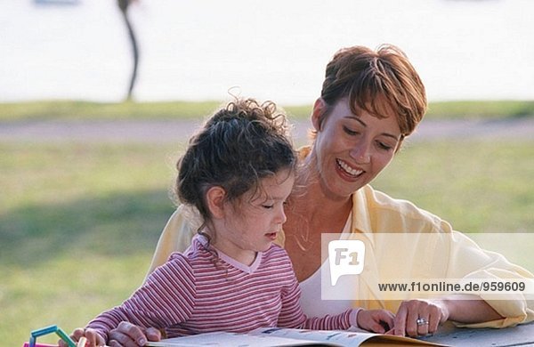 Mutter und Tochter lesen zusammen im park