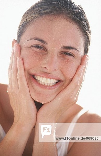 Young adult Woman mit klare Haut spritzendes Wasser auf ihrem Gesicht