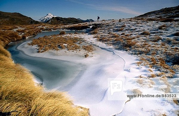 Tramper near frozen tarn. Kelly Range. Arthur´s Pass NP. New Zealand
