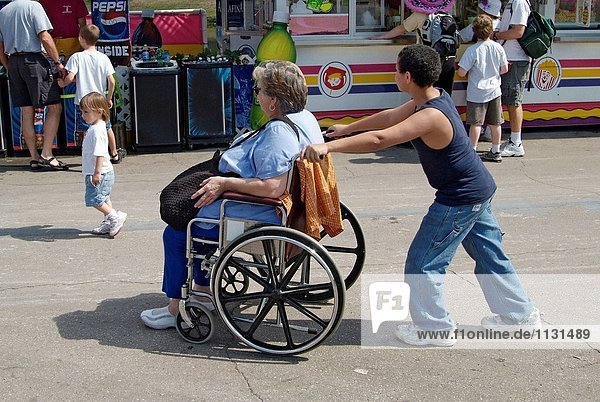 Enkel treibt Großmutter in einem Rollstuhl.