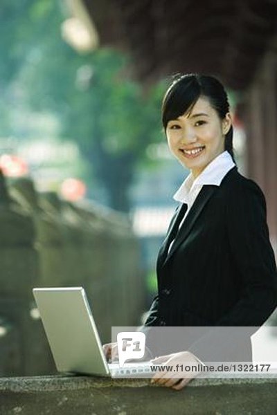 Young woman standing next to laptop  portrait