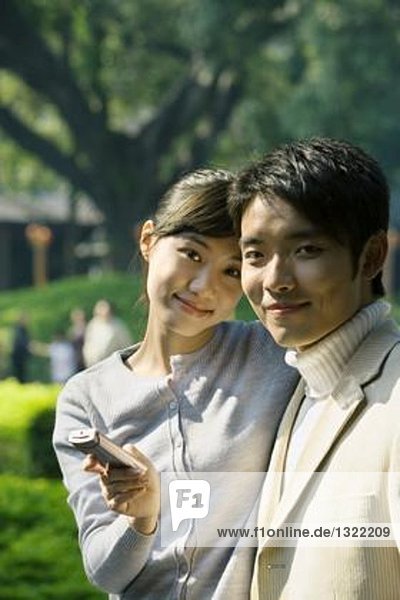 Young couple with cell phone  smiling at camera  portrait