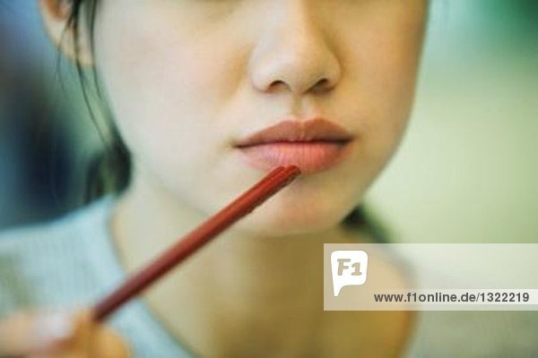 Young woman eating with chopsticks