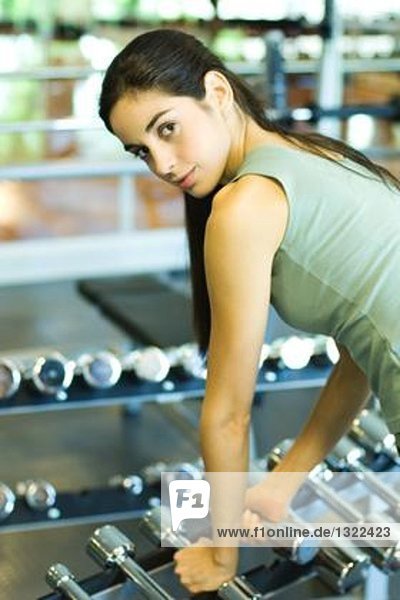 Woman picking up weights  looking over shoulder at camera