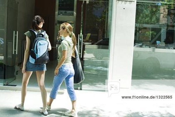 Two young women walking toward doorway together