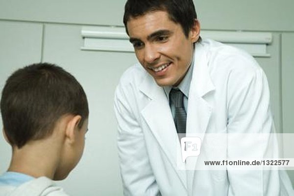 Doctor leaning forward  smiling at little boy