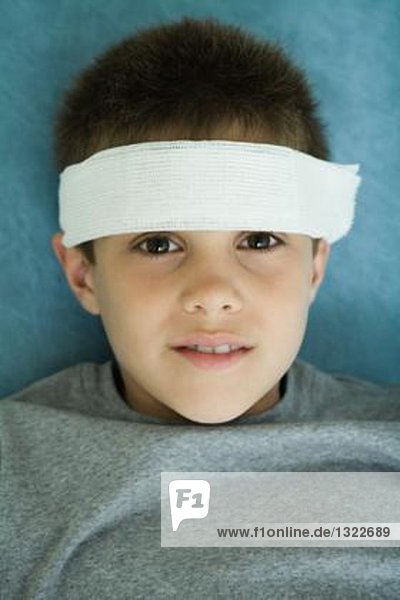 Junge mit Stirnbandage  Portrait  Blick in die Kamera
