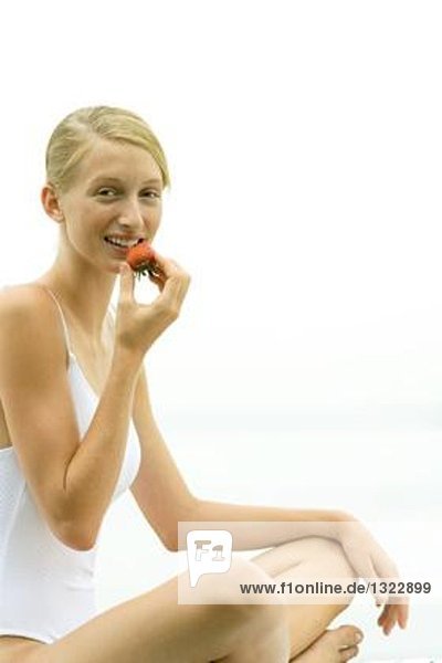 Teenage girl wearing bathing suit  eating strawberry  smiling