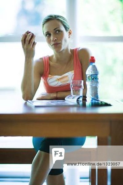 Junge Frau in Sportbekleidung mit Snack in der Cafeteria des Fitnessclubs