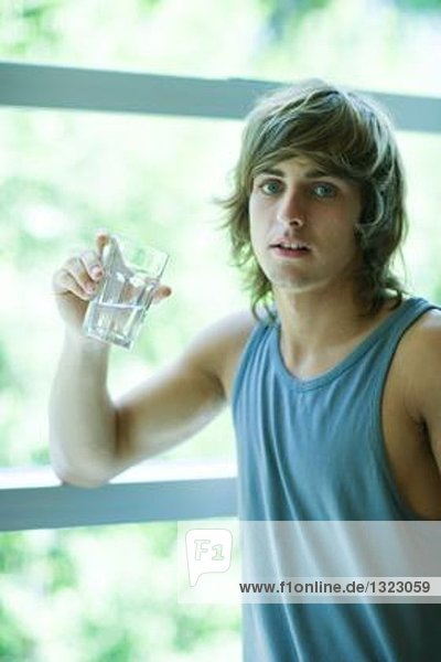 Junger Mann in Trainingskleidung trinkt Wasserglas