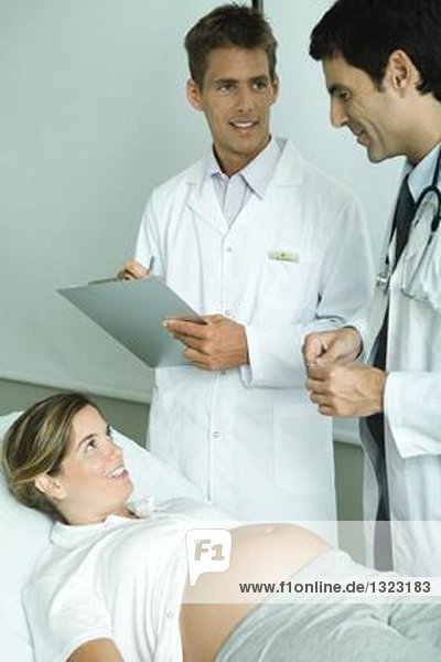 Zwei Ärzte im Gespräch mit einer schwangeren Frau