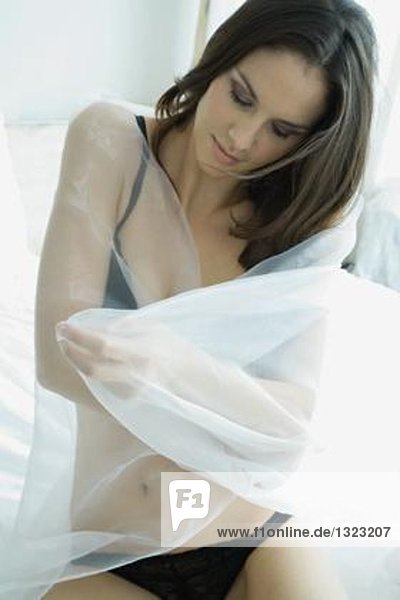 Woman in underwear wrapping self in sheer material