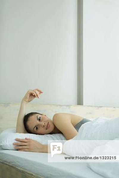 Young woman lying in bed  smiling