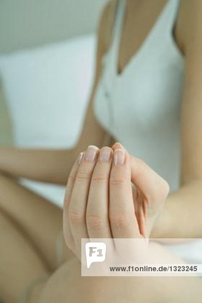 Woman sitting in lotus position  cropped view  focus on hand in foreground