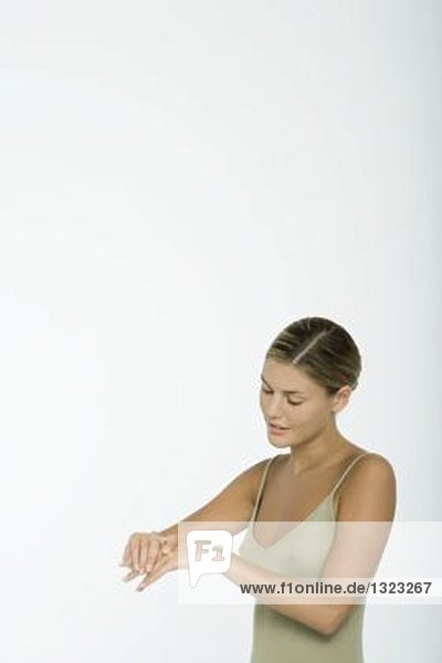 Young woman moisturizing hands