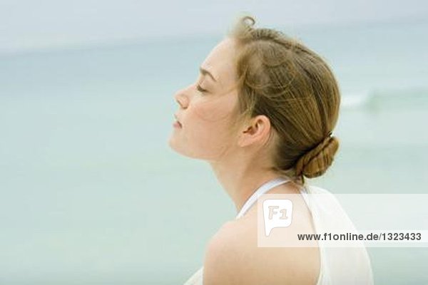 Junge Frau  Kopf und Schultern  Seitenansicht  Meer im Hintergrund