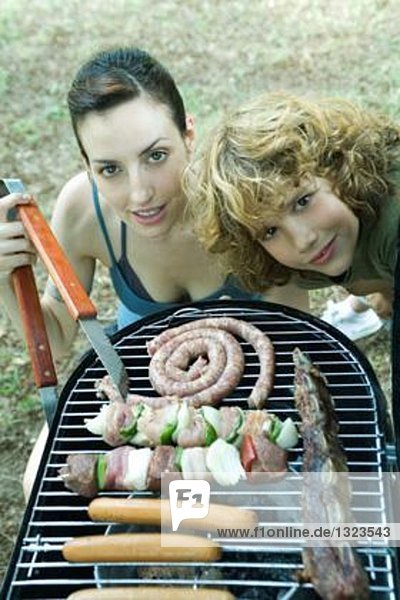 Familie beim Kochen  Frau und Junge neben dem Barbecue  lächelnd vor der Kamera