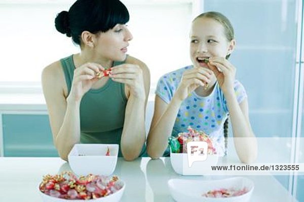 Junge Frau und junges Mädchen essen Süßigkeiten