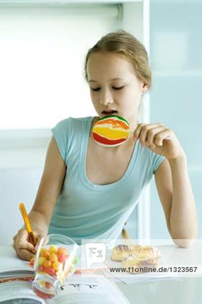 Mädchen macht Hausaufgaben und isst Junk Food