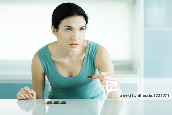 Frau isst Schokoladenstücke  schaut weg