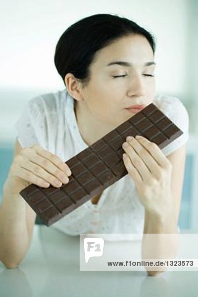 Frau hält große Tafel Schokolade  Augen geschlossen