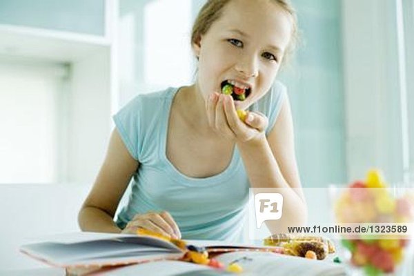 Mädchen beim Essen von Junk Food bei den Hausaufgaben