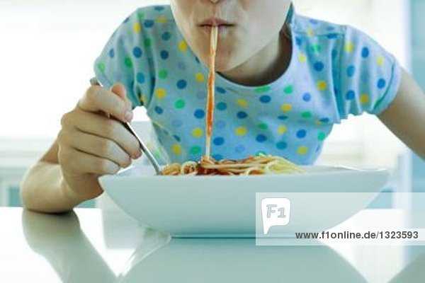 Mädchen essen Spaghetti mit Tomatensauce  Schnittansicht