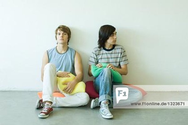 Teenager-Freunde sitzen auf Kissen auf dem Boden  volle Länge
