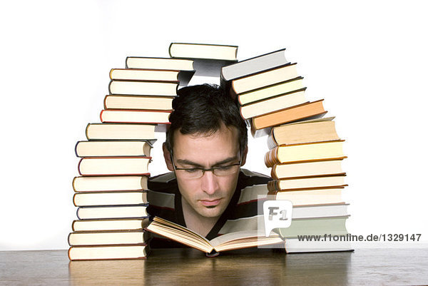 Junger Mann beim Lesen von gestapelten Büchern  Nahaufnahme
