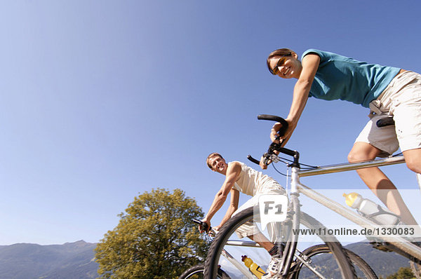 Junges Paar auf dem Mountainbike,  lächelnd,  Blickwinkel niedrig