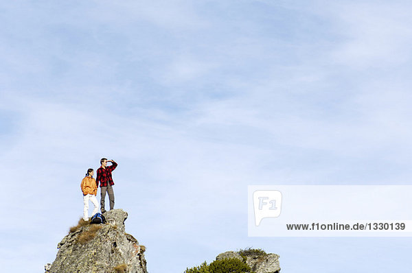 Junges Paar auf dem Berggipfel stehend,  wegschauend