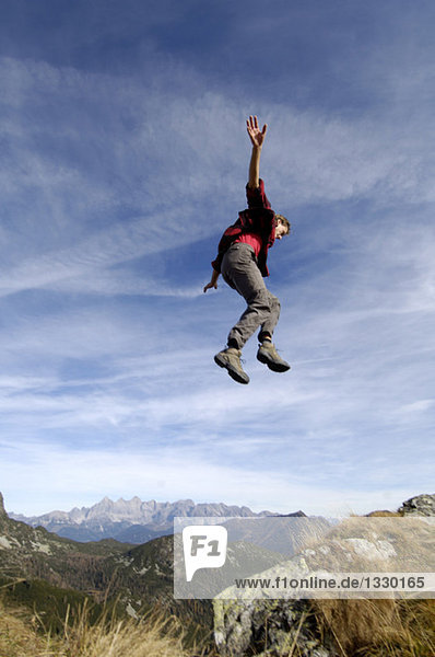 Mann springt über Berge,  Arme ausstrecken,  Seitenansicht