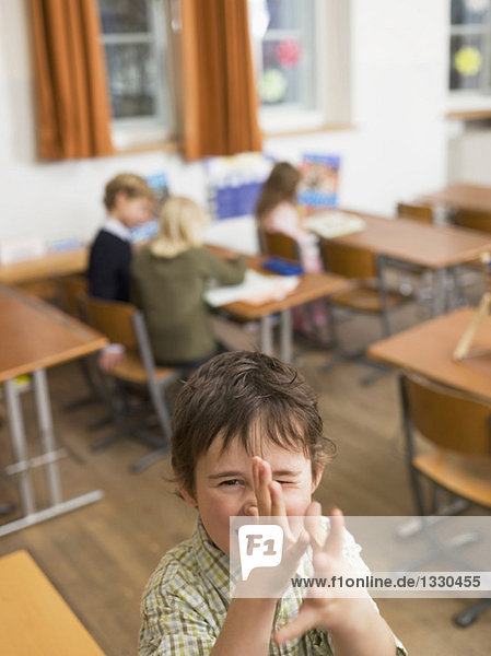 Children (4-7) in class room  focus on boy gesturing in foreground  elevated view