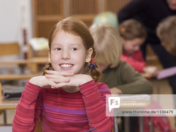 Mädchen (4-7) im Klassenzimmer  lächelnd  Kopf an den Händen  Nahaufnahme