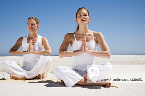 Zwei Frauen beim Yoga am Strand