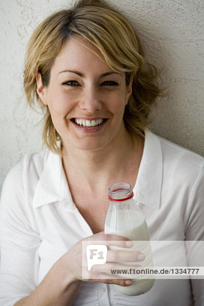 Junge Frau hält eine Flasche Milch in der Hand