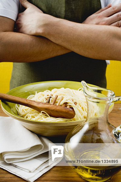 A dish of spaghetti with spaghetti server and olive oil