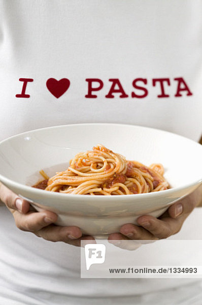 Frau hält Pastateller mit Spaghetti & Tomatensauce