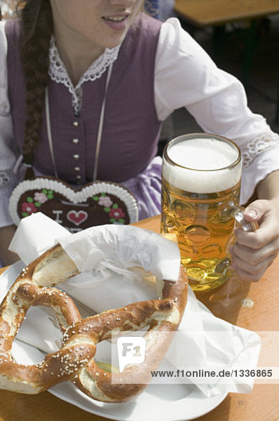 Frau mit Mass Bier und Brezel beim Oktoberfest