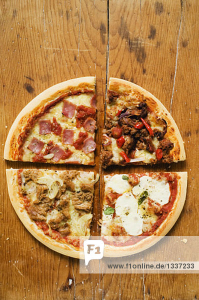 Vier verschiedene Pizzastücke auf Holzuntergrund