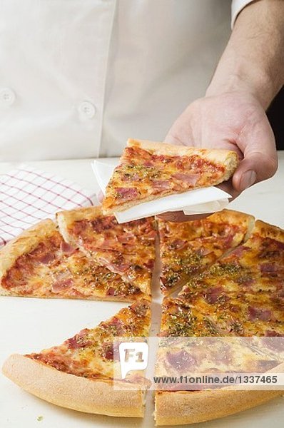 Chef holding slice of American-style ham pizza